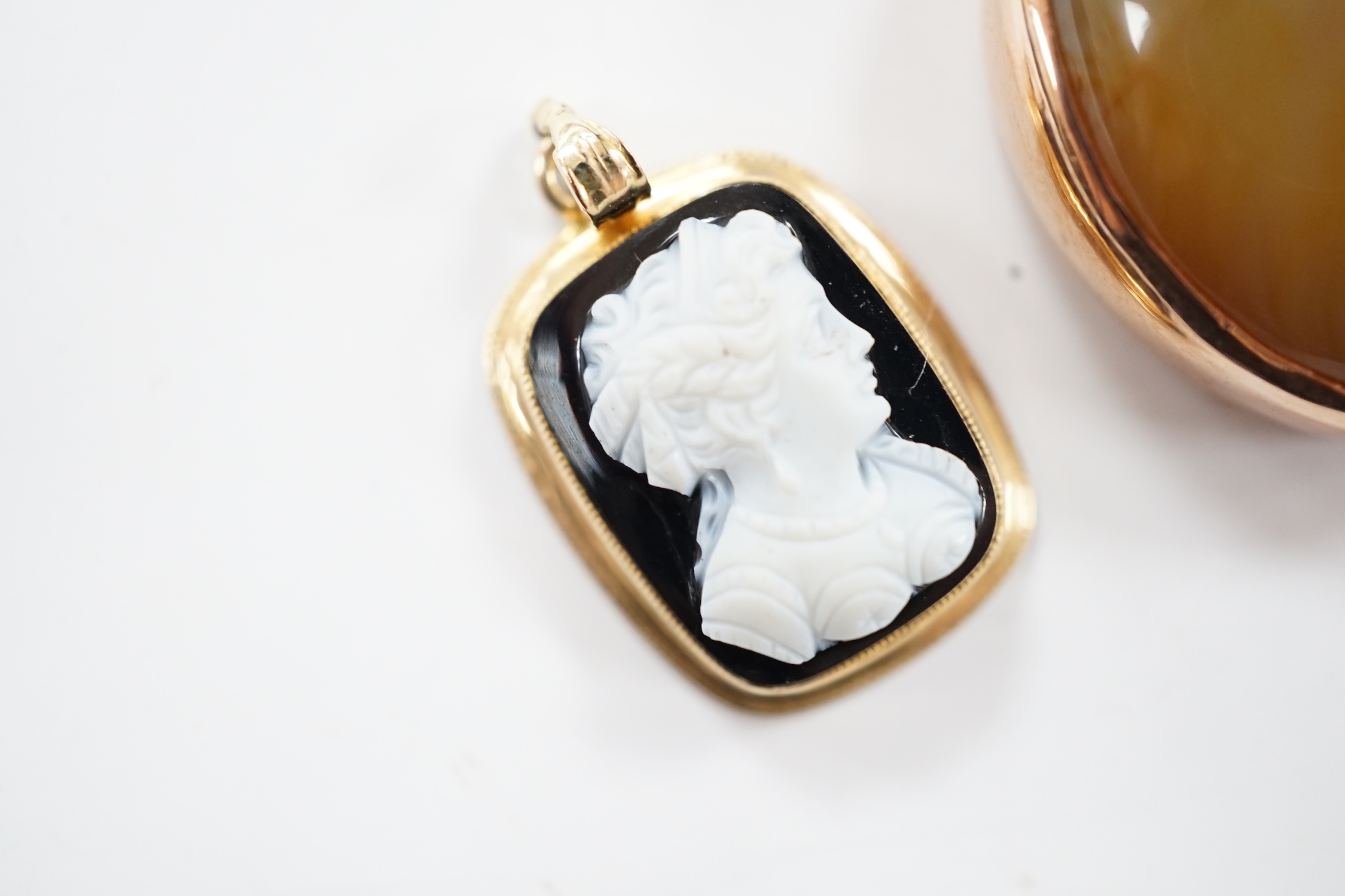 A yellow metal mounted oval banded agate pendant, 26mm and a smaller yellow metal mounted sardonyx cameo pendant.